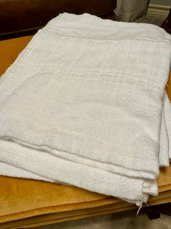 A folded achromatic  towel sits connected  a woody  surface, suggesting an point  disposable  for purchase