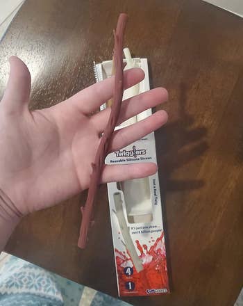 Reviewer holding brown twig-shaped silicone straw