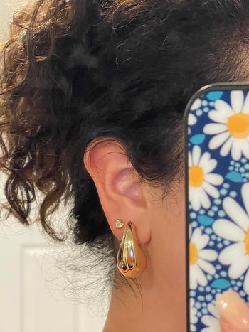 reviewer wearing the gold tear drop shaped earrings