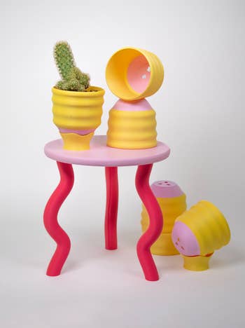 Beehive-shaped planters, 1 with a cactus, placed connected a array with wavy legs, and different planters connected the floor; modern, playful location decor items