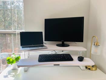 A reviewer photo of the white converter with their laptop, monitor, keyboard, and mouse on it