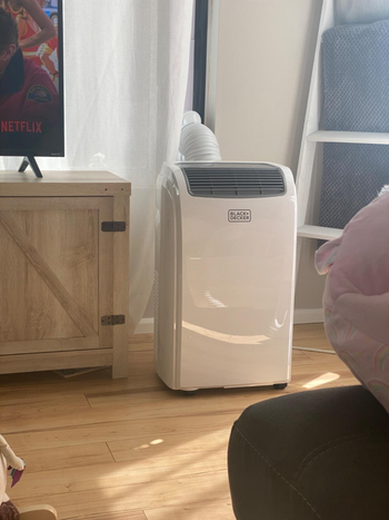 reviewer photo of the white portable air conditioner set up in a living room