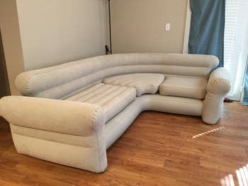 Reviewer image of tan blow up couch in an L-shape in corner of a room