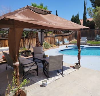 reviewer photo of the brown pop up gazebo next to a pool