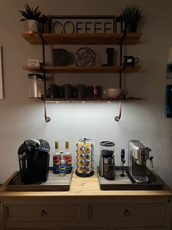 a reviewer photo of shelves with lights installed underneath over a coffee bar 