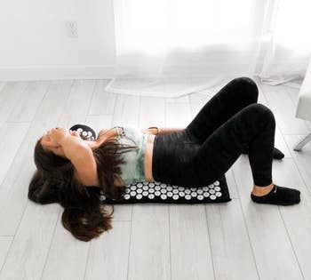 reviewer laying on black accupressure mat