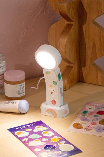 the lamp turned on on a desk with the two sticker sheets