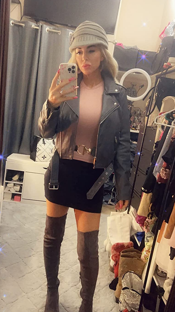 reviewer wearing the gray jacket over a pink top with a black skirt and thigh-high boots