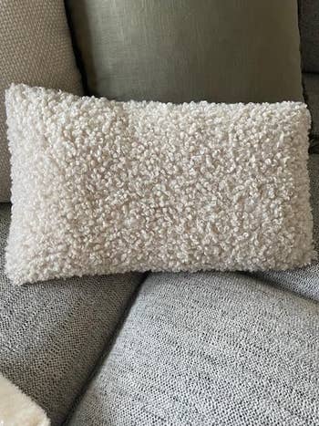 A textured, boucle propulsion  pillow connected  a sofa, highlighting a cozy location  decor point  perfect  for buying  considerations