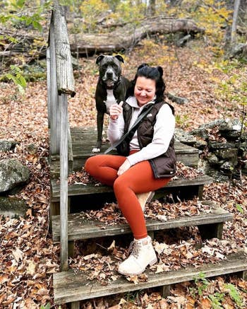 reviewer successful  casual outdoor attire sits connected  woody  steps with a dog, surrounded by fallen leaves successful  a forest