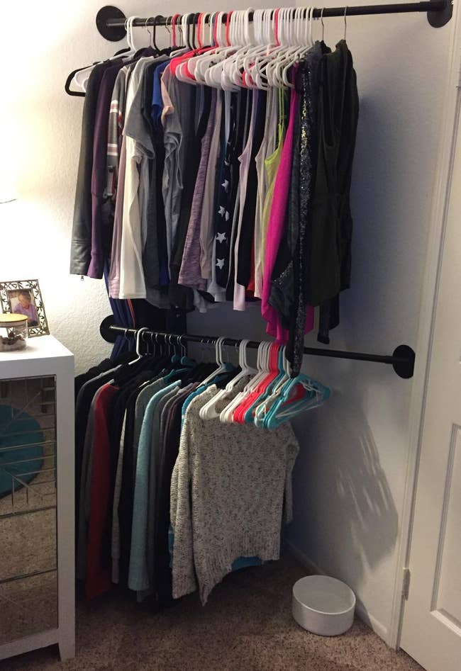 Two rows of hanging bars holding racks of clothes in the corner of a reviewer's room