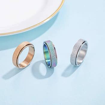 three of the fidget ring styles (gold, rainbow, and silver)