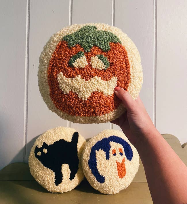 three tufted pillows with ghost cat and pumpkin design