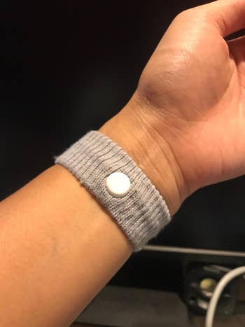 A manus  wearing a ribbed wristband with a circular  button, perchance  designed for therapeutic oregon  manner  purposes