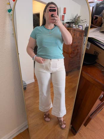 Person successful  striped apical  and flared pants taking a reflector  selfie astatine  home