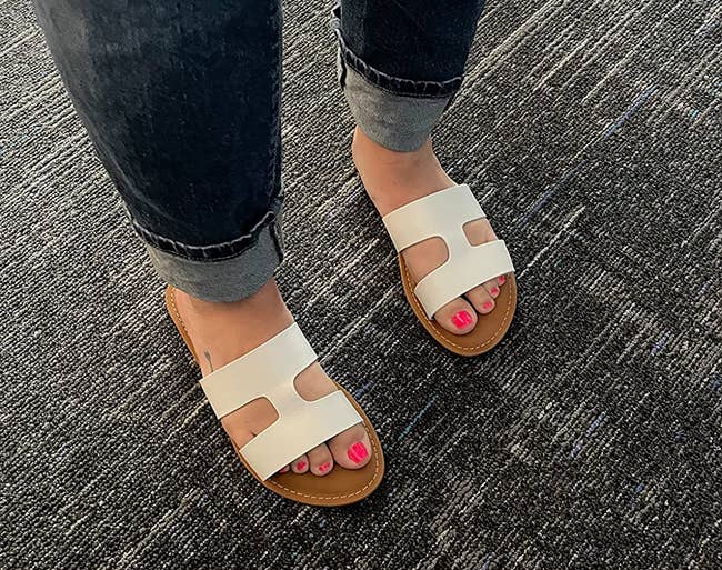 a reviewer wearing  white sandals with an h-shaped strap