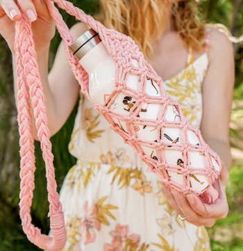 A model holding up the holder in pink with a water bottle inside of it