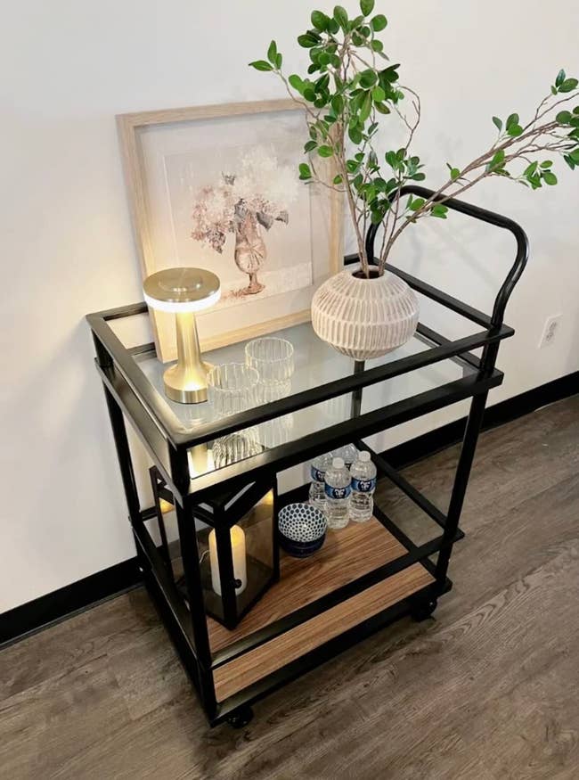 a reviewer's black bar cart with top shelf of glass and bottom of wood