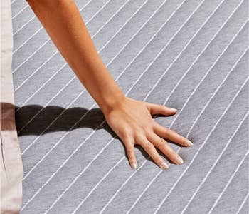 a model pressing their hand on a gray mattress