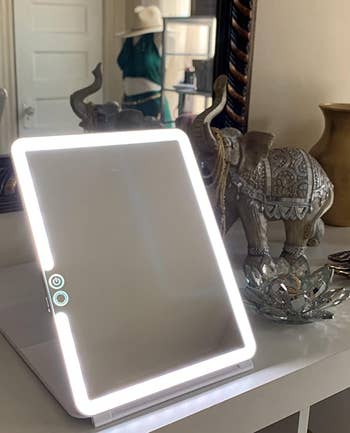 reviewer photo of the lit travel mirror propped up on a table