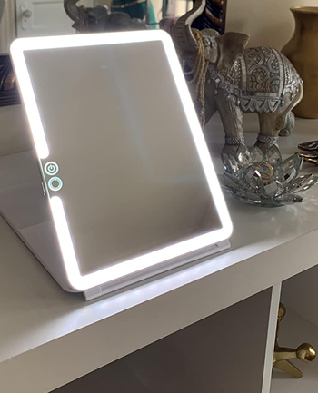 reviewer photo of the lit travel mirror propped up on a table