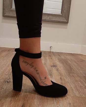 reviewer's foot wearing the black heel