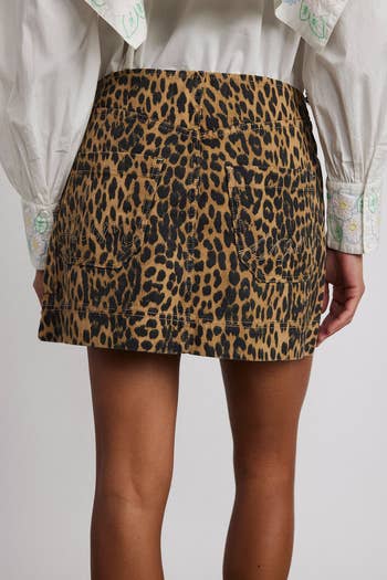 Person wearing a leopard print skirt with pockets, paired with a white blouse. Perfect for a chic look