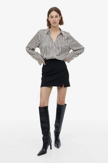 model wearing black and white striped button-up tucked into a black mini skirt