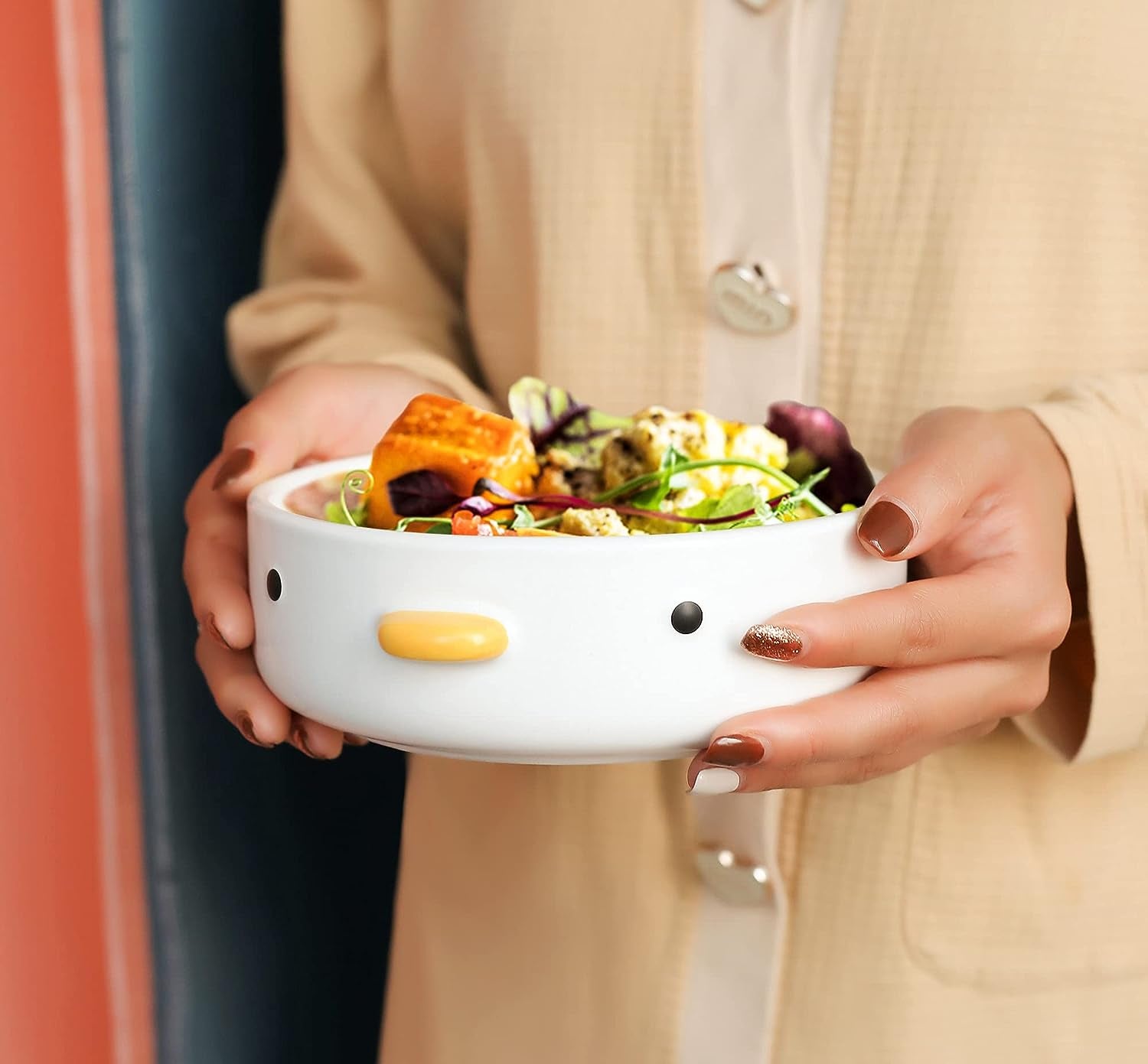 A round flat bowl with a duck face on it full of salad 