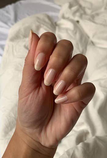 Reviewer displaying manicured nails with glossy finish, likely showcasing a nail product for shopping purposes