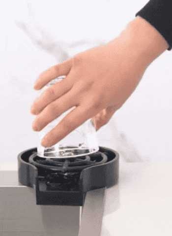 Model using a flat round rinser to press a cup onto so it will spray a jet of water up into it to clean 