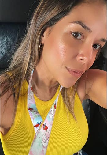 Person in a sleeveless top with a floral lanyard takes a selfie in a car