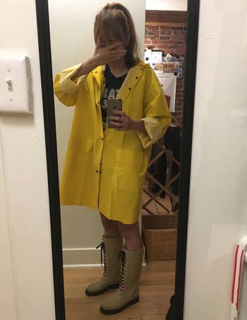reviewer selfie wearing the oversized yellow trench raincoat