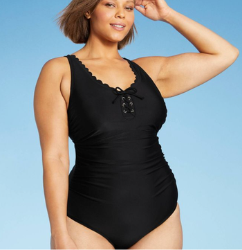 Model in a black suit with scalloped collar and tie at the bust 