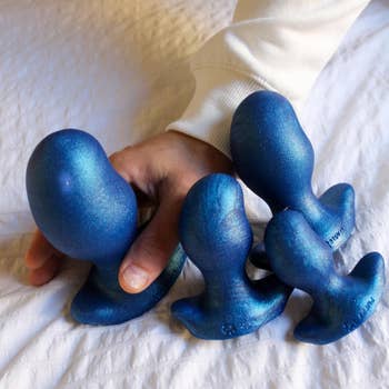 Model with assortment of blue butt plugs in various sizes