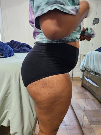 reviewer showing side view of black cotton underwear