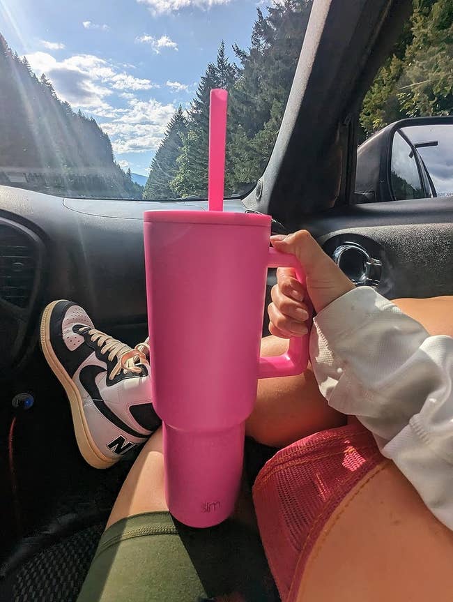 reviewer in car holding pink water bottle tumbler with handle
