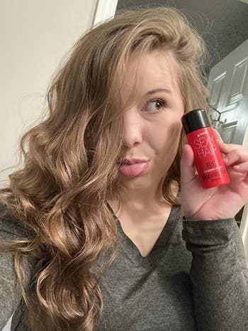 reviewer with voluminous wavy hair and holding the powder