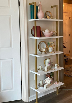 reviewer photo of the gold and white bookshelf holding pieces of decor