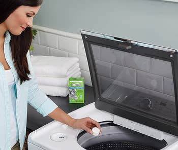 a model dropping a cleaning tablet into a washing machine