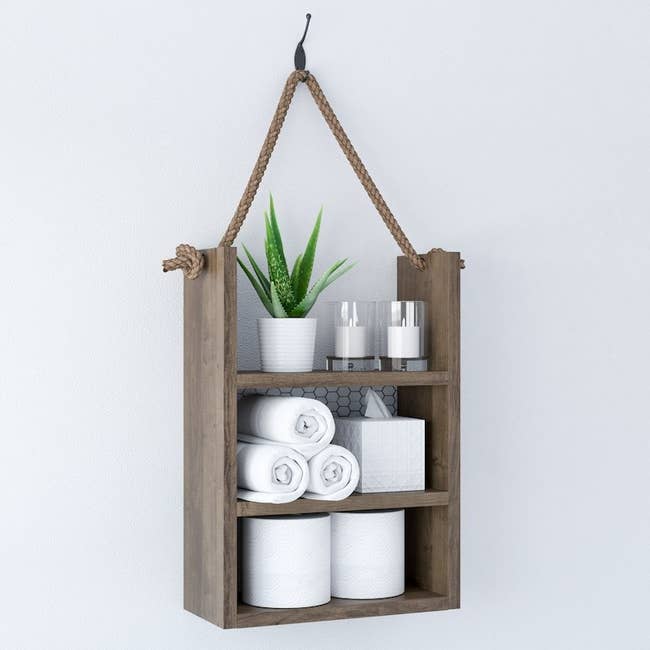 the hanging shelf with toilet paper, tissues, and towels