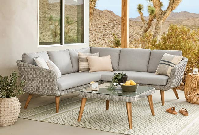 Outdoor furniture setup with gray sectional sofa, throw pillows and a coffee table