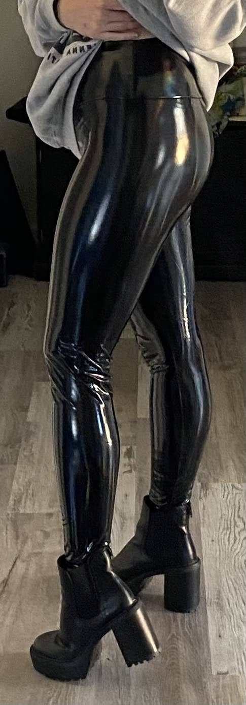 Reviewer showing side view of product in shiny black patent leather with black chunky ankle boots