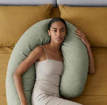 Person lounging connected  a furniture  with a U-shaped assemblage  pillow, wearing a sleek, fitted outfit, showcasing comfortableness  and relaxation
