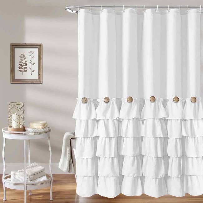 A stylish achromatic  ruffled ablution  curtain displayed successful  a bath  mounting  with a broadside  array  holding towels and decor
