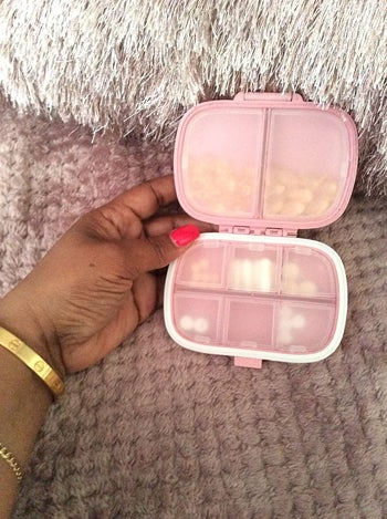 Reviewer showing pink open pill case with full compartments