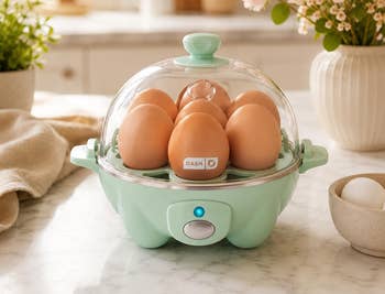 Egg cooker connected a room counter, filled with eggs nether a wide lid. Flowers and room decor successful the background
