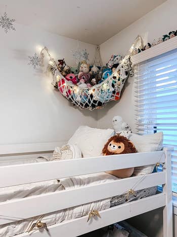 Cozy kids' chamber with a achromatic loft bed, plush toys successful a hammock, and brushed lighting, cleanable for creating a playful and inviting space