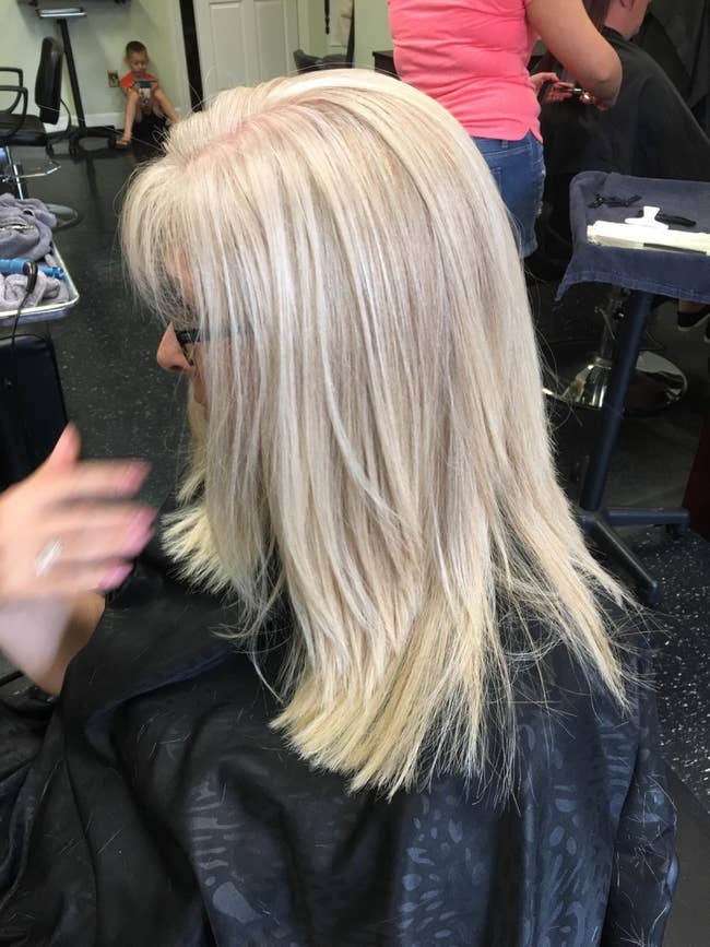 Woman astatine a salon wearing a cape, getting her hairsbreadth styled, highlighting modern hairsbreadth trends for buying and quality articles