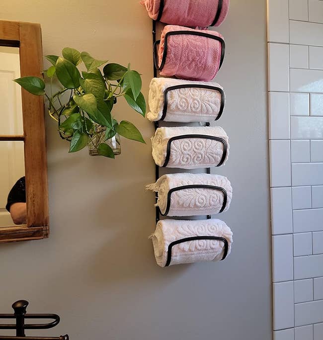 reviewer's black towel rack holding six rolled up towels